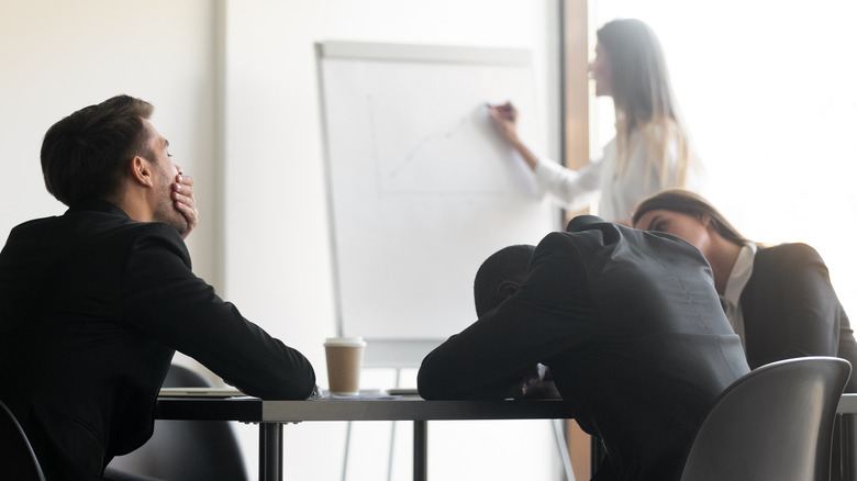 Employees yawning and bored at work meeting