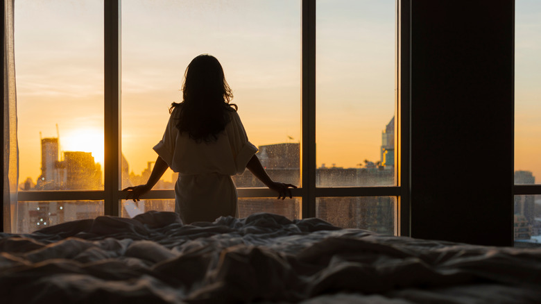 woman looking at sunrise out of window