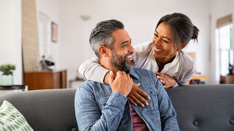 Smiling couple embrace on couch