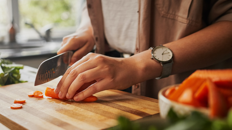 woman chopping carrots on a cutting board