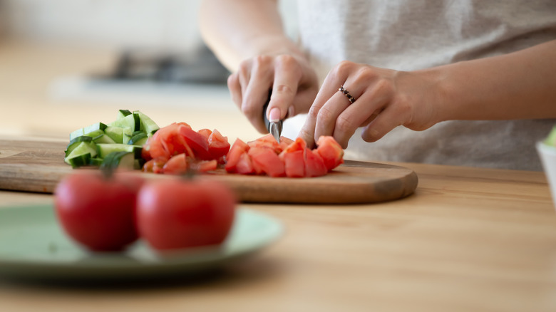 a woman cutting tomatoes on a cutting board