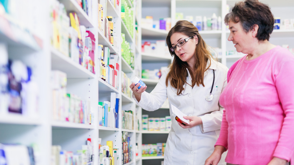 A pharmacist and a customer reviewing medications on shelves