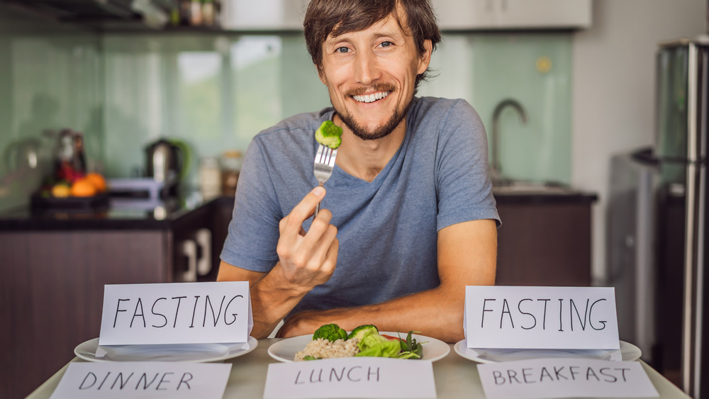 Man smiling with signs about fasting