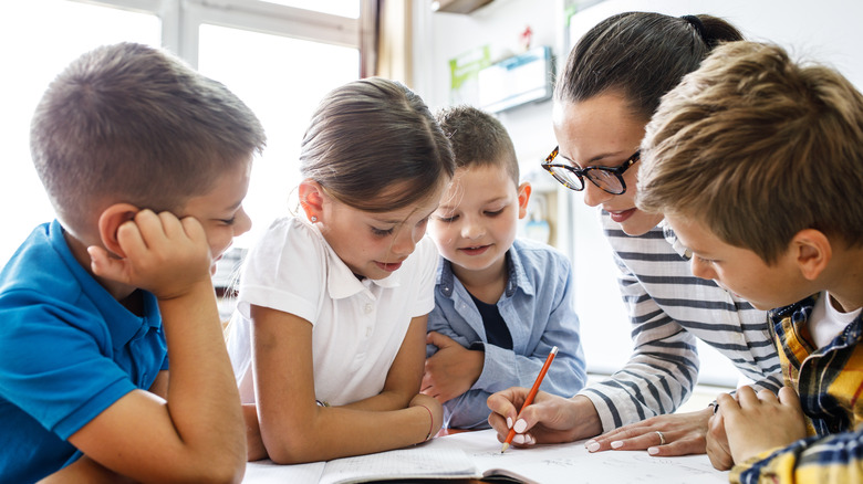 children and a teacher at a table in school