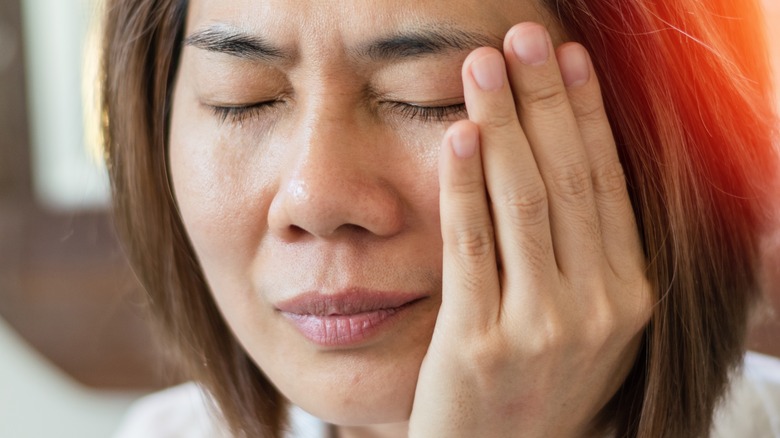 woman holding one side of face