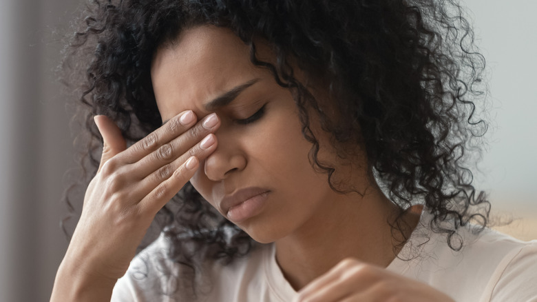 woman with curly hair rubbing eyes