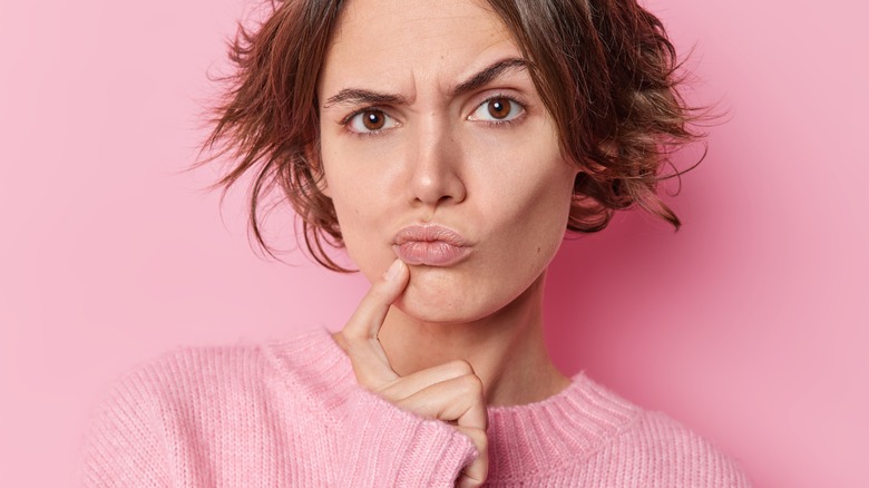 woman raising eyebrow with pink background