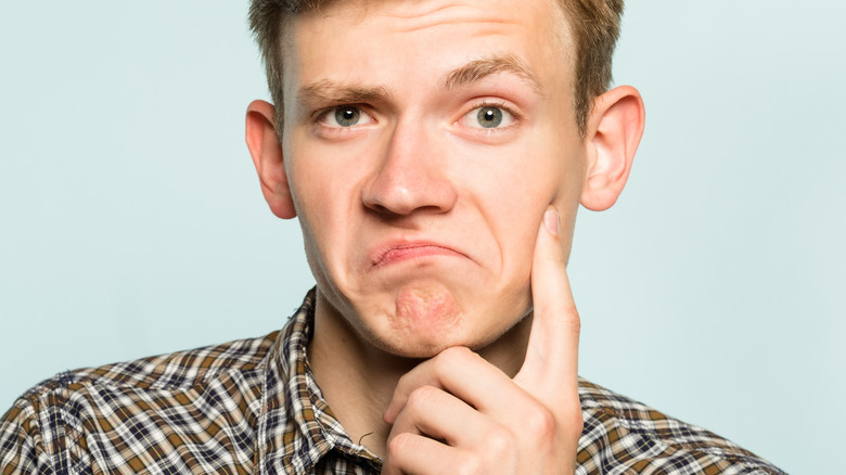 man raising eyebrow and touching cheek