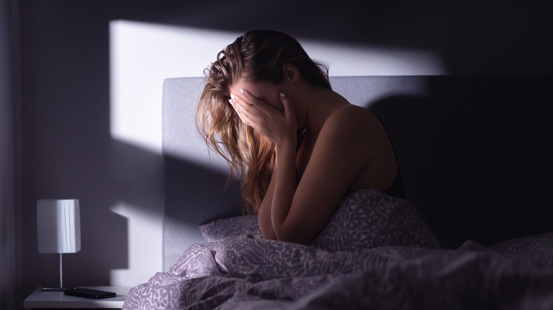anxious woman sitting on bed at night 