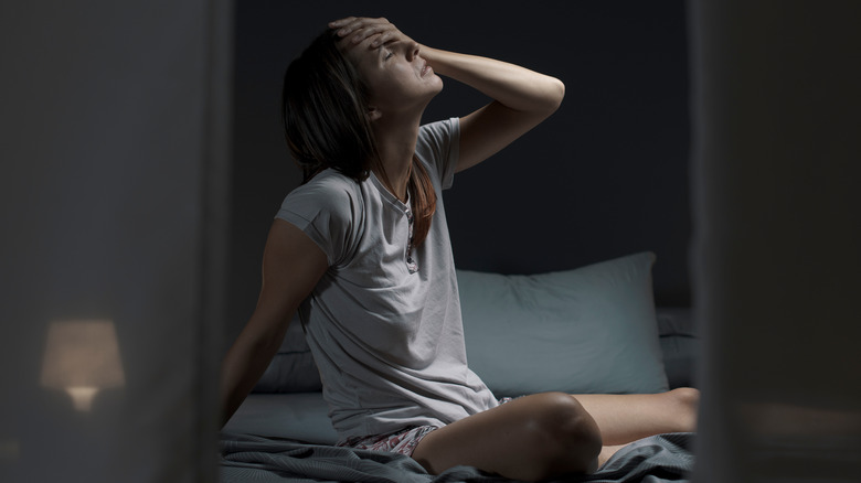 woman sitting up in bed sweating 