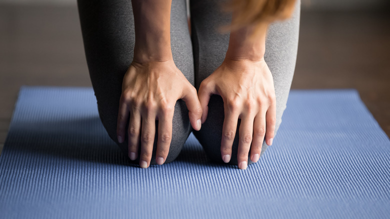 person holding knees on yoga mat