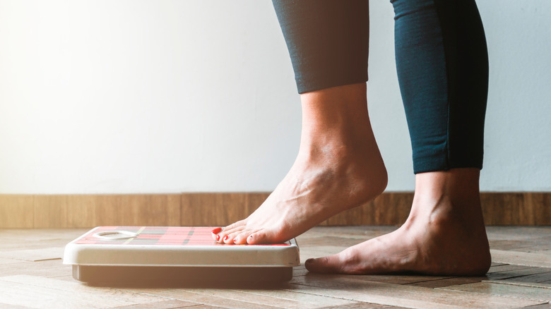 close up of a woman stepping onto a scale at home