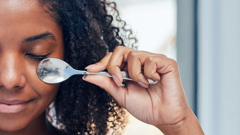 Woman applying spoon to face