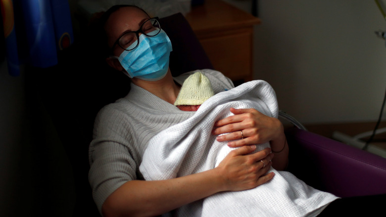 masked woman holds preterm baby