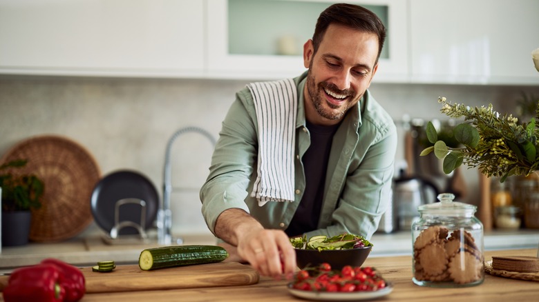 man reaching for a cherry tomato for his salad