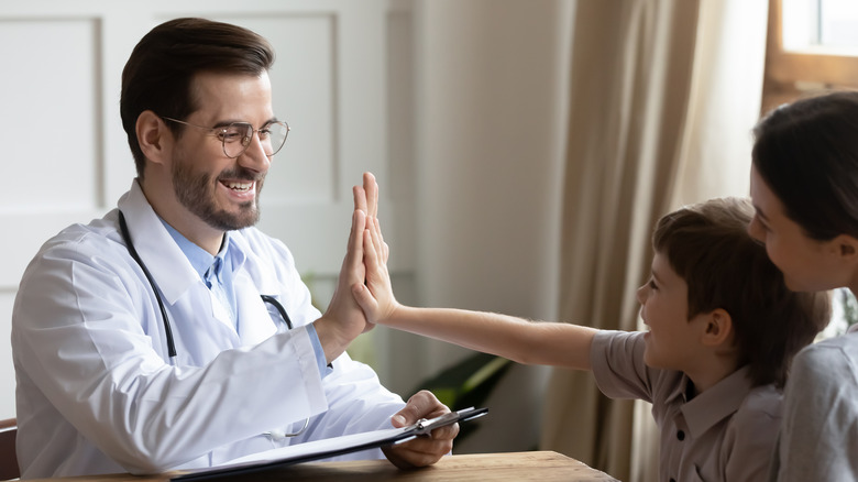 A pediatrician high fives a child