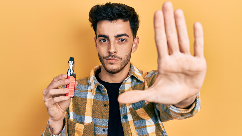 Young man holding e-cigarette and hand in stop motion