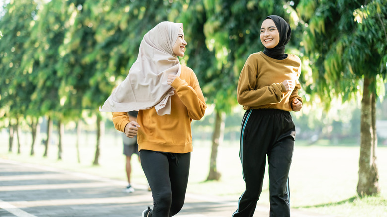 Two girls wearing hijab jog together in a park