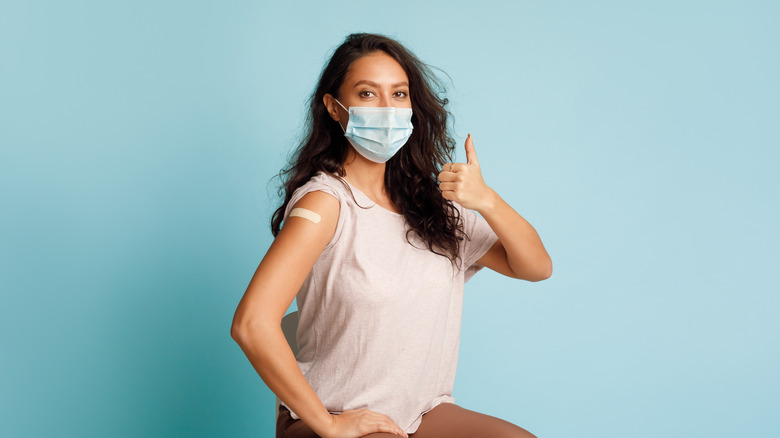 woman with mask holding thumbs up after vaccination