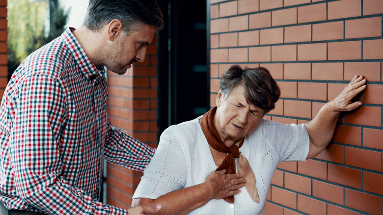 man helping woman with chest pain