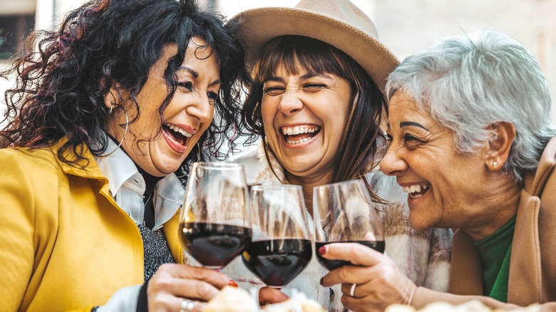 Group of laughing women drinking wine