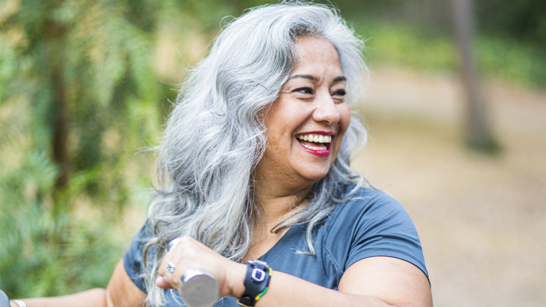 Smiling woman exercising outside with weights