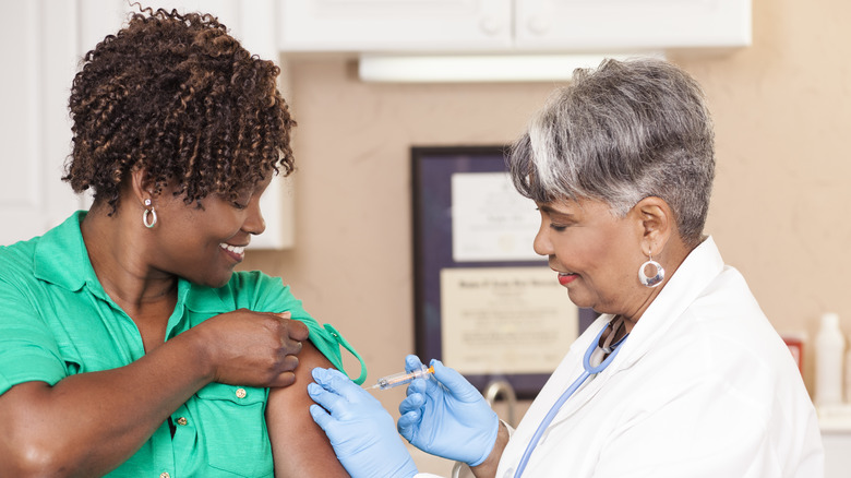 Smiling woman receiving a vaccine from doctor