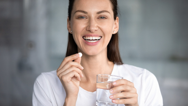 smiling woman holding a pill