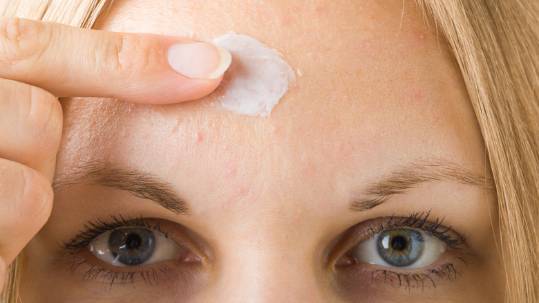 close up of woman applying product to forehead