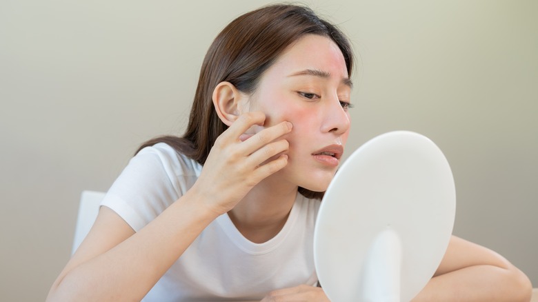 woman looking at face in mirror