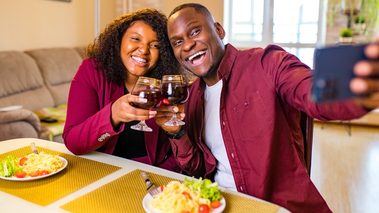 smiling couple holding glasses of red wine