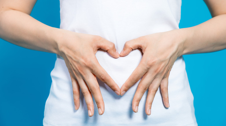 close up of stomach with hands showing heart symbol