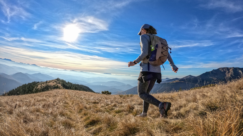 woman walking with rucksack with mountains in the horizon