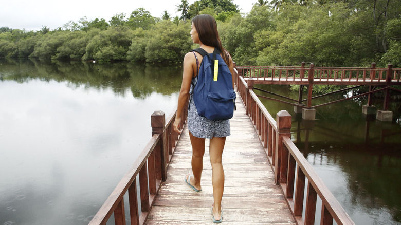 Woman carrying backpack crossing pedestrian bridge