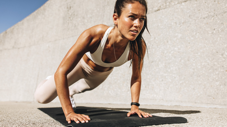 woman doing pushups on concrete