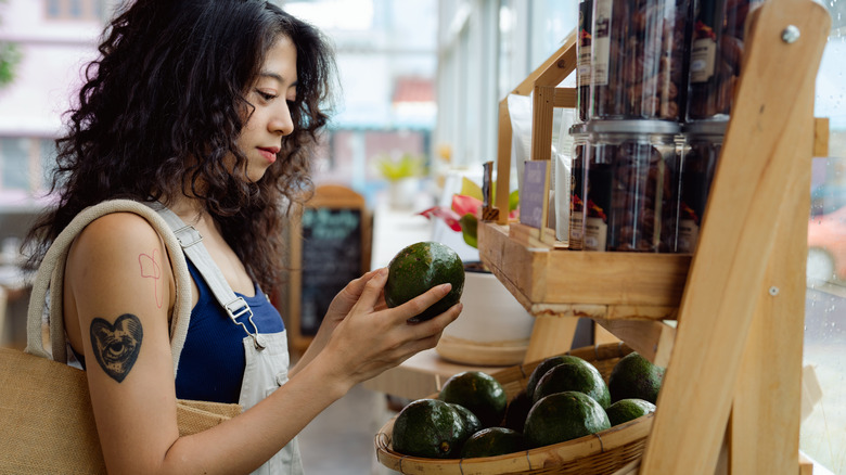 Woman grocery shopping for avocado