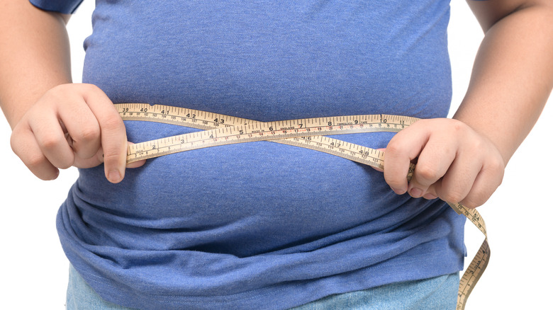 Overweight boy measuring his stomach