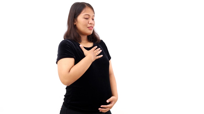 Pregnant woman with hand on chest and belly
