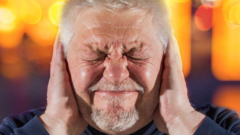 Elderly man covering ears