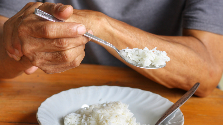 Man steadying hand tremor while eating