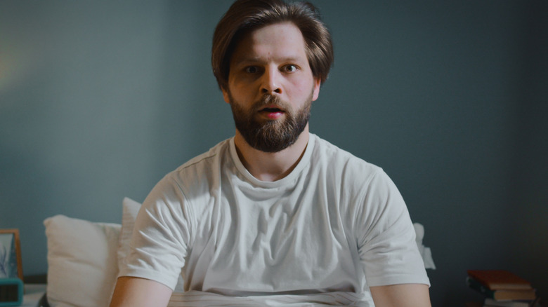 A man sits up in his bed after having a nightmare