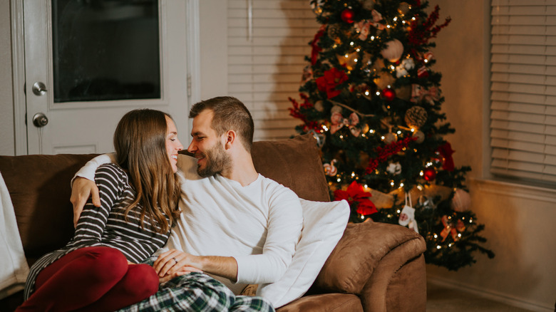 couple on couch in front of christmas tree