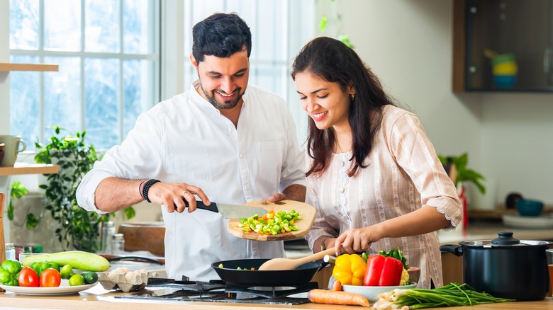 couple cooking vegetables in kitchen