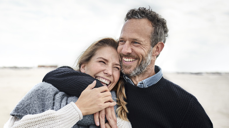 A middle-aged couple embracing on the beach