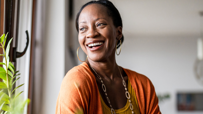 A woman in her 50s smiling as she looks out the window