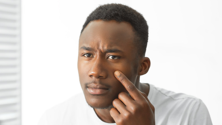 Man looking at skin in mirror