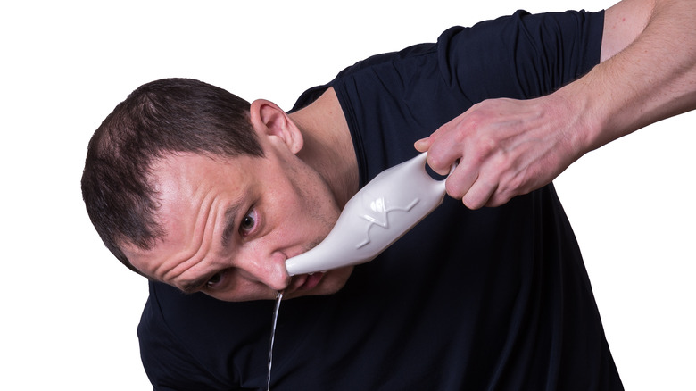 Man using neti pot to clean nose