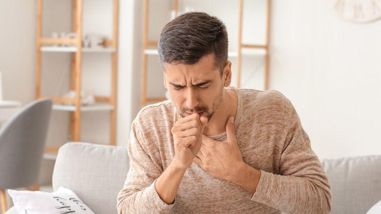 Man coughing at home on couch