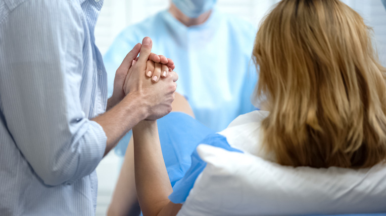 Man holding wife's hand for support during childbirth