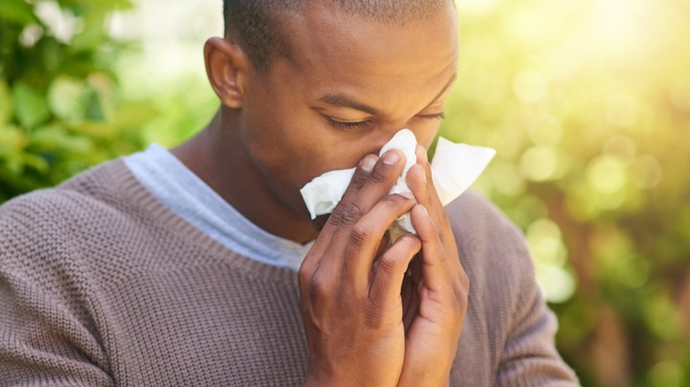 Man blowing nose into tissue